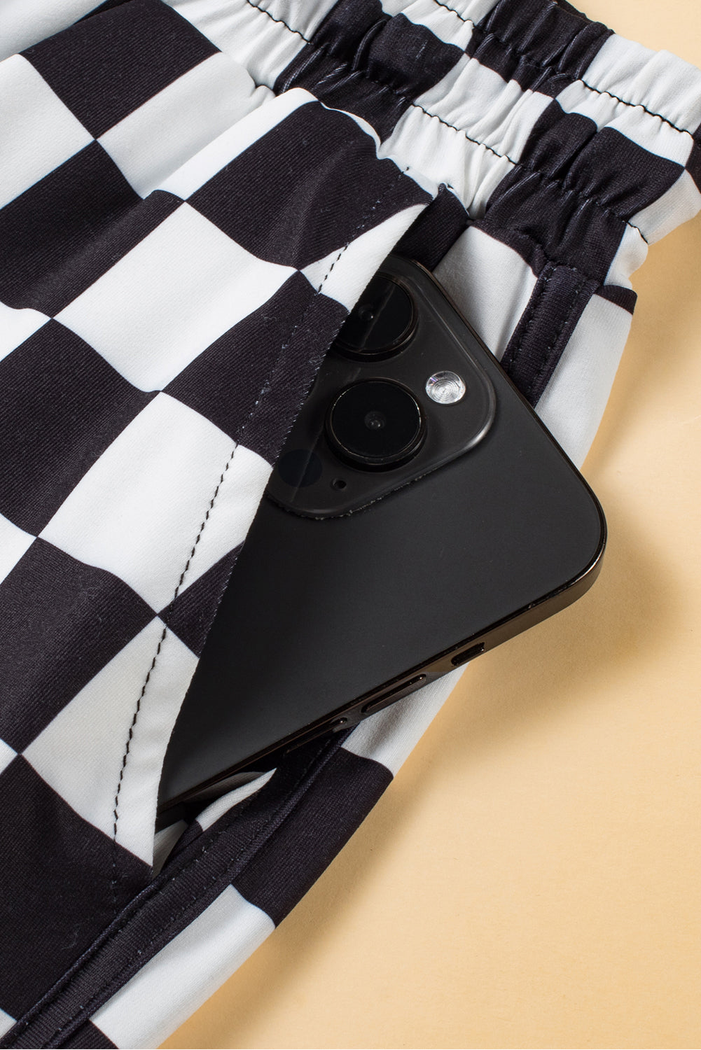 Black and white checkerboard lounge shorts with a phone in the pocket.
