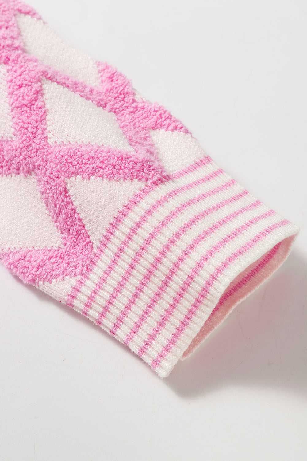 Diamond jacquard knit cardigan in blush pink with striped cuffs.