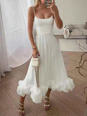White midi dress with spaghetti straps and a ruffled hem.