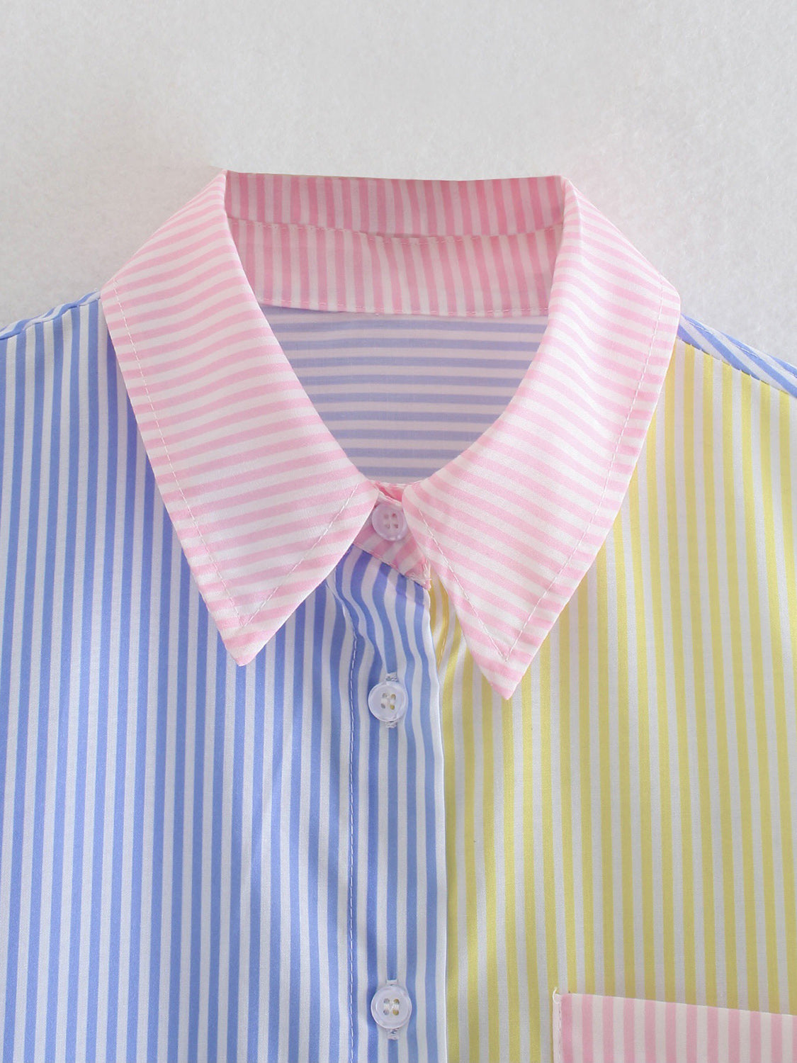 Colorblock striped oversized button-down shirt with pink collar and blue, yellow, and pink panels.