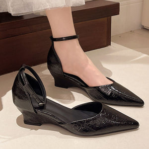 Black pointed-toe wedge heels with ankle strap and adjustable buckle.