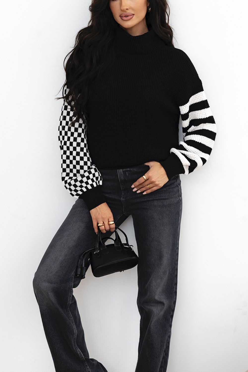 Black knit turtleneck sweater with checkerboard and stripe sleeves