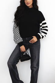 Black knit turtleneck sweater with checkerboard and stripe sleeves