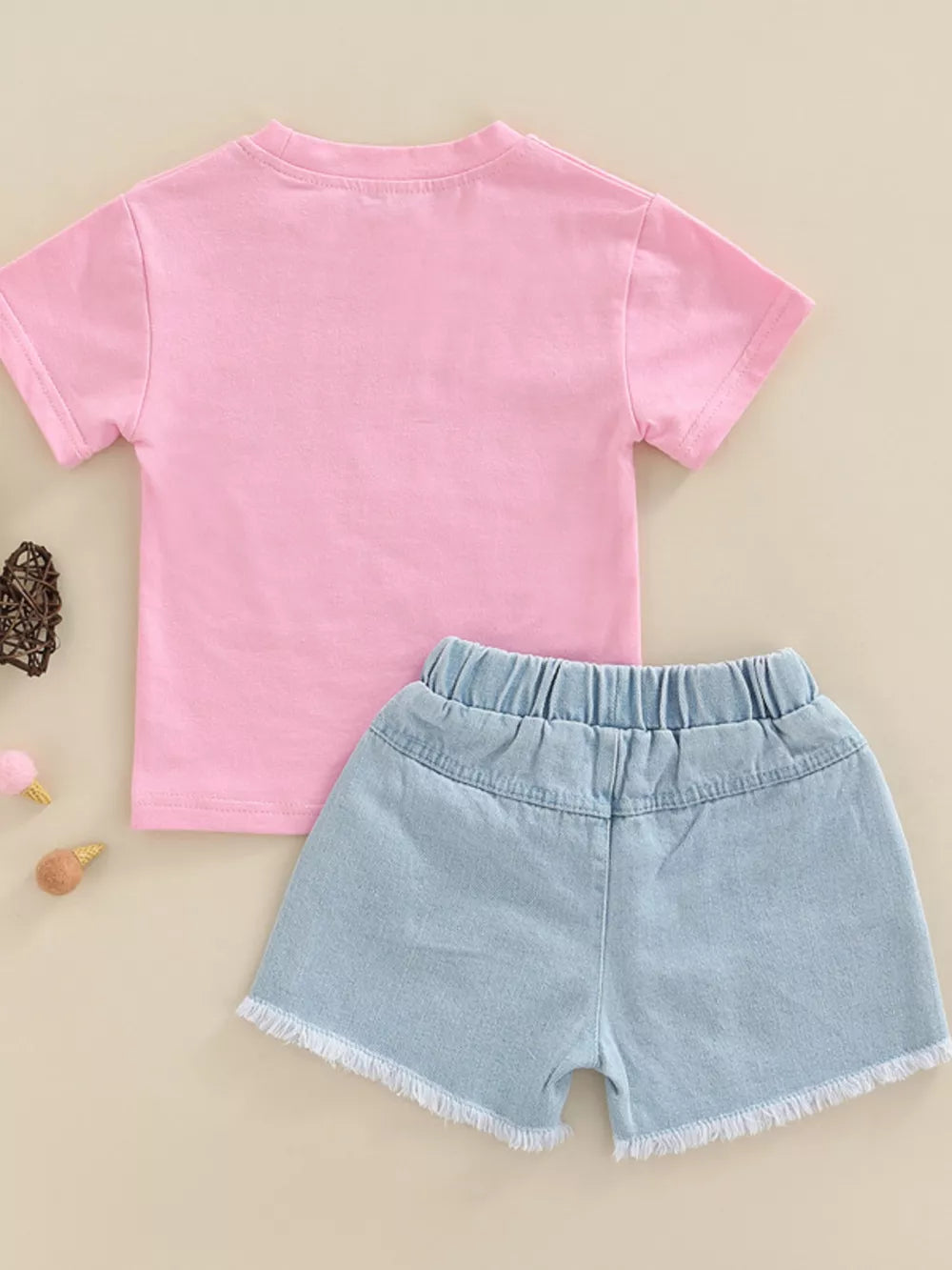 Pink cotton tee and light wash distressed denim shorts with frayed hem.