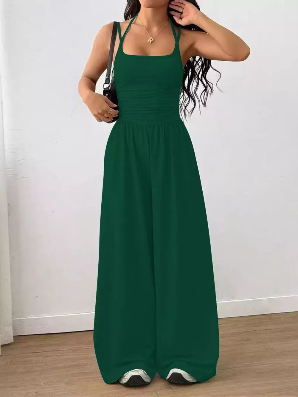 Dark green ruched wide-leg jumpsuit with square neckline and spaghetti straps.
