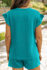Turquoise textured co-ord set with flutter sleeves and geometric pattern.