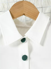 White baby top with green buttons and collar detail