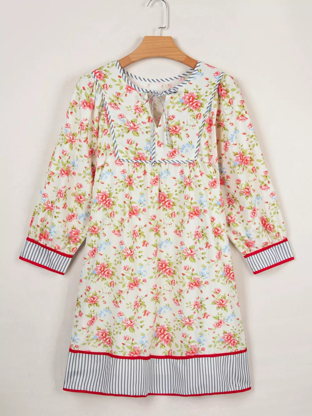 Floral cotton dress with puff sleeves, tie neck, and striped trim.