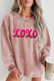 Textured ribbed dusty pink sweatshirt with pink and gold XOXO appliqué detail.