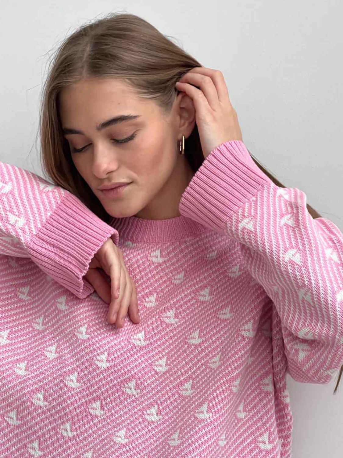 Blush pink knit sweater with sailboat jacquard pattern and ribbed cuffs.