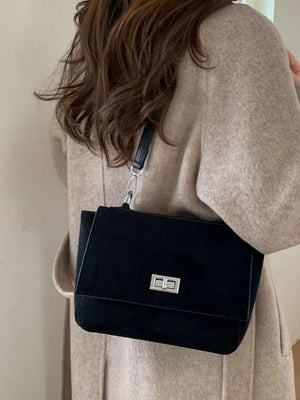 Black suede crossbody bag with flap closure and silver hardware.