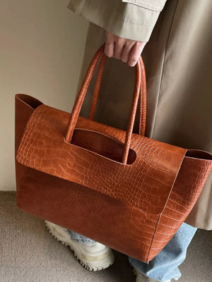 Brown crocodile-embossed medium tote bag with top handles and a structured flap detail.