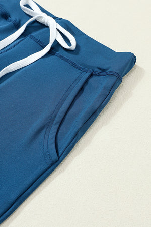 Slim-fit dark blue drawstring joggers with white tie and side pocket detail.