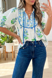 White floral tie-neck shirt with blue embroidery and puff sleeves