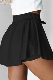 Black flared skort with tie waist and elastic waistband, A-line cut.