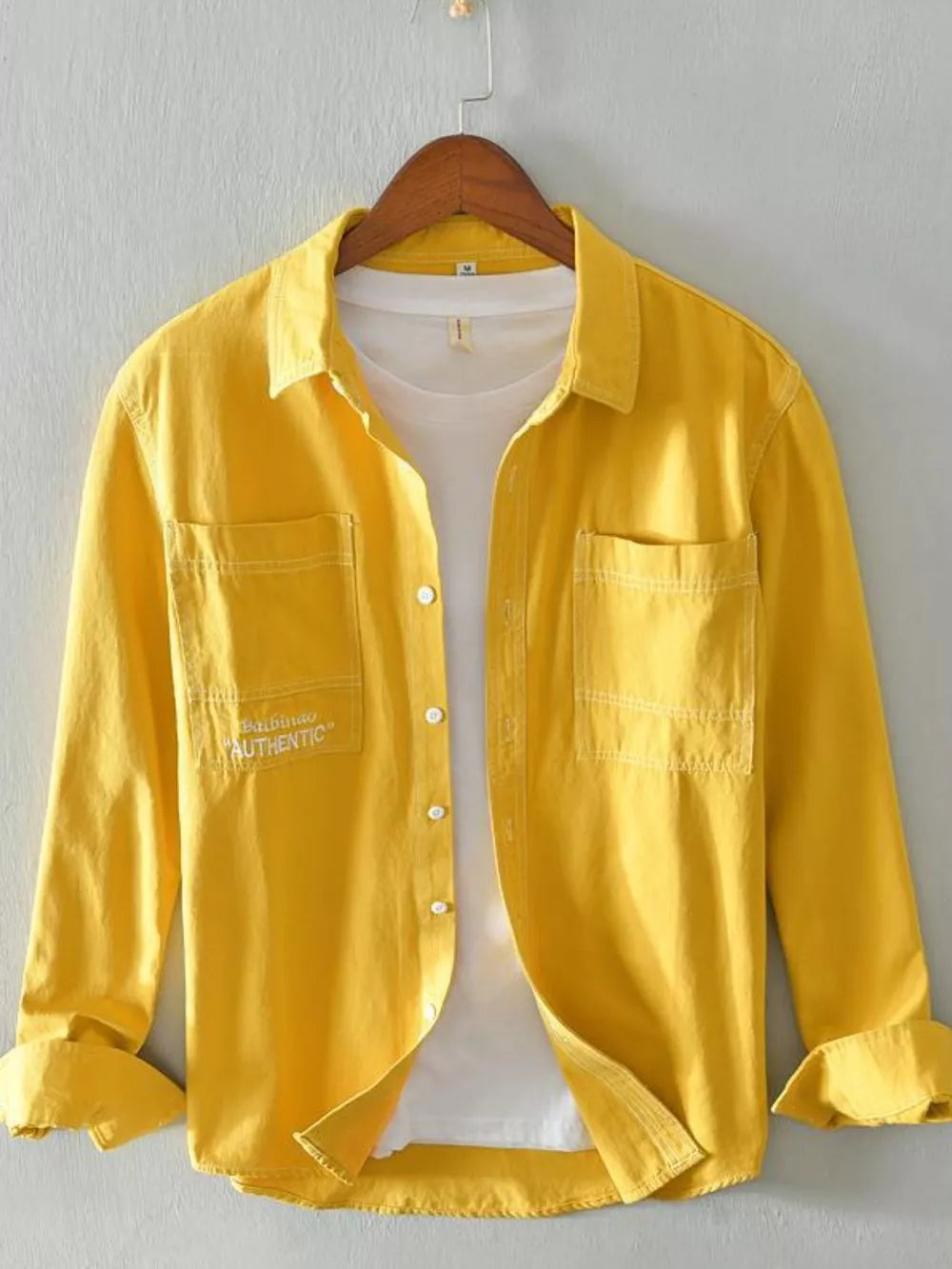 Yellow men's button-up shirt with contrast stitching, two chest pockets, and white undershirt.