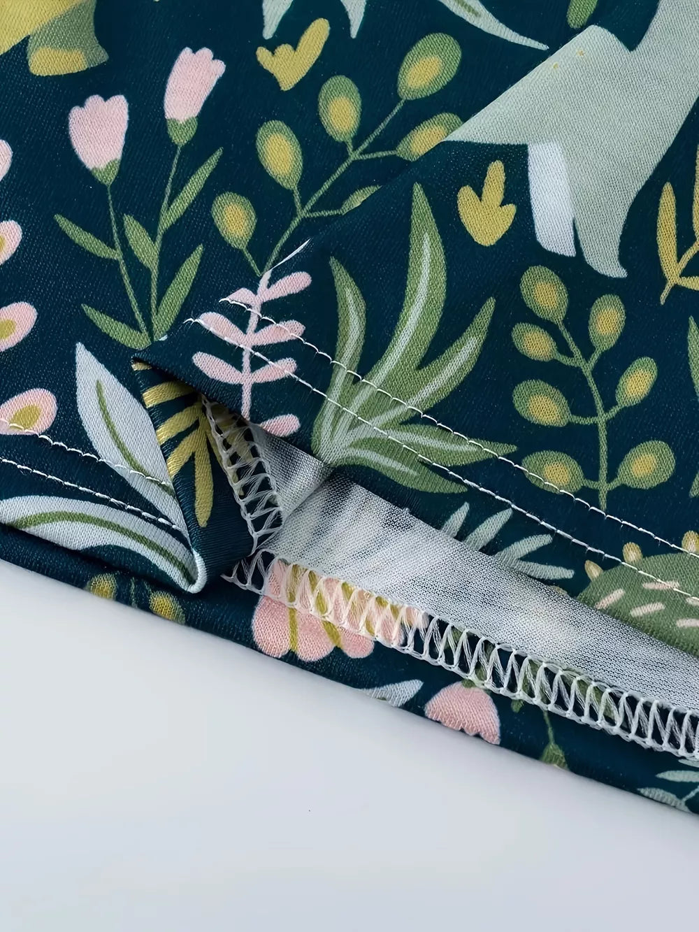 Dinosaur print elastic waist skirt in dark blue with pink flowers and green leaves.