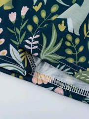 Dinosaur print elastic waist skirt in dark blue with pink flowers and green leaves.