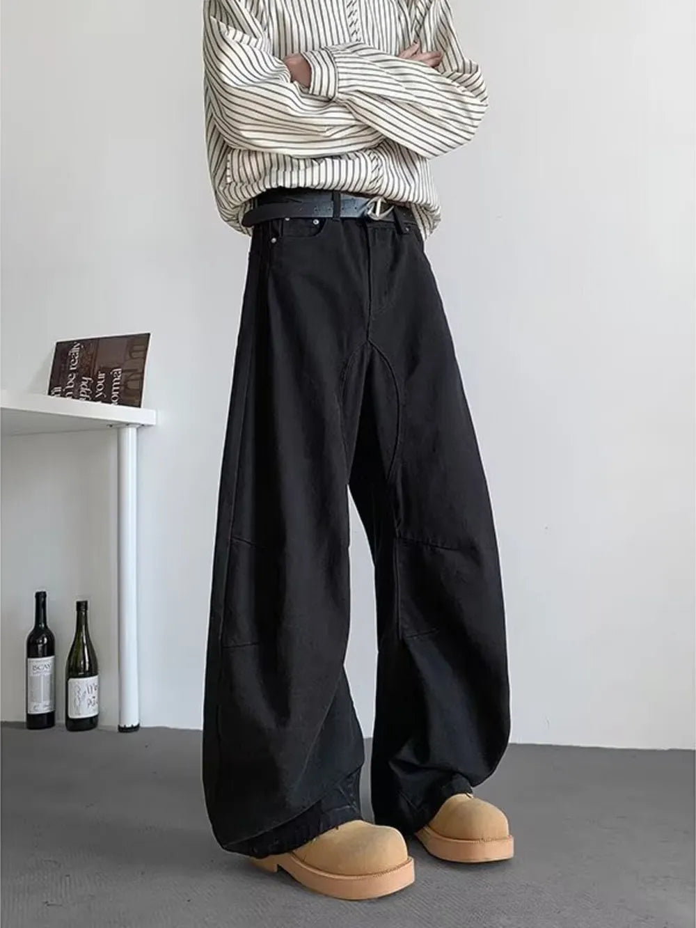 Black men's baggy sweatpants with pockets and a belted waist, styled with a striped shirt.