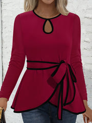 Burgundy peplum blouse with keyhole neckline, tie detail, and black trim.