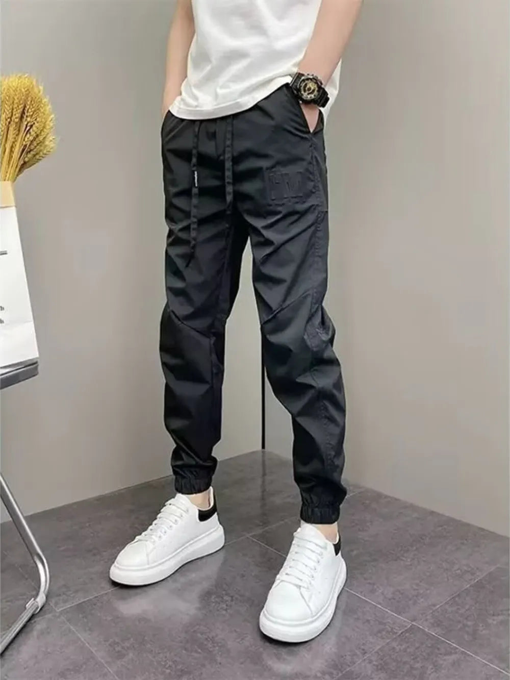 Black cotton drawstring sweatpants with elastic cuffs and a subtle embossed logo detail.