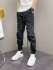 Black cotton drawstring sweatpants with elastic cuffs and a subtle embossed logo detail.