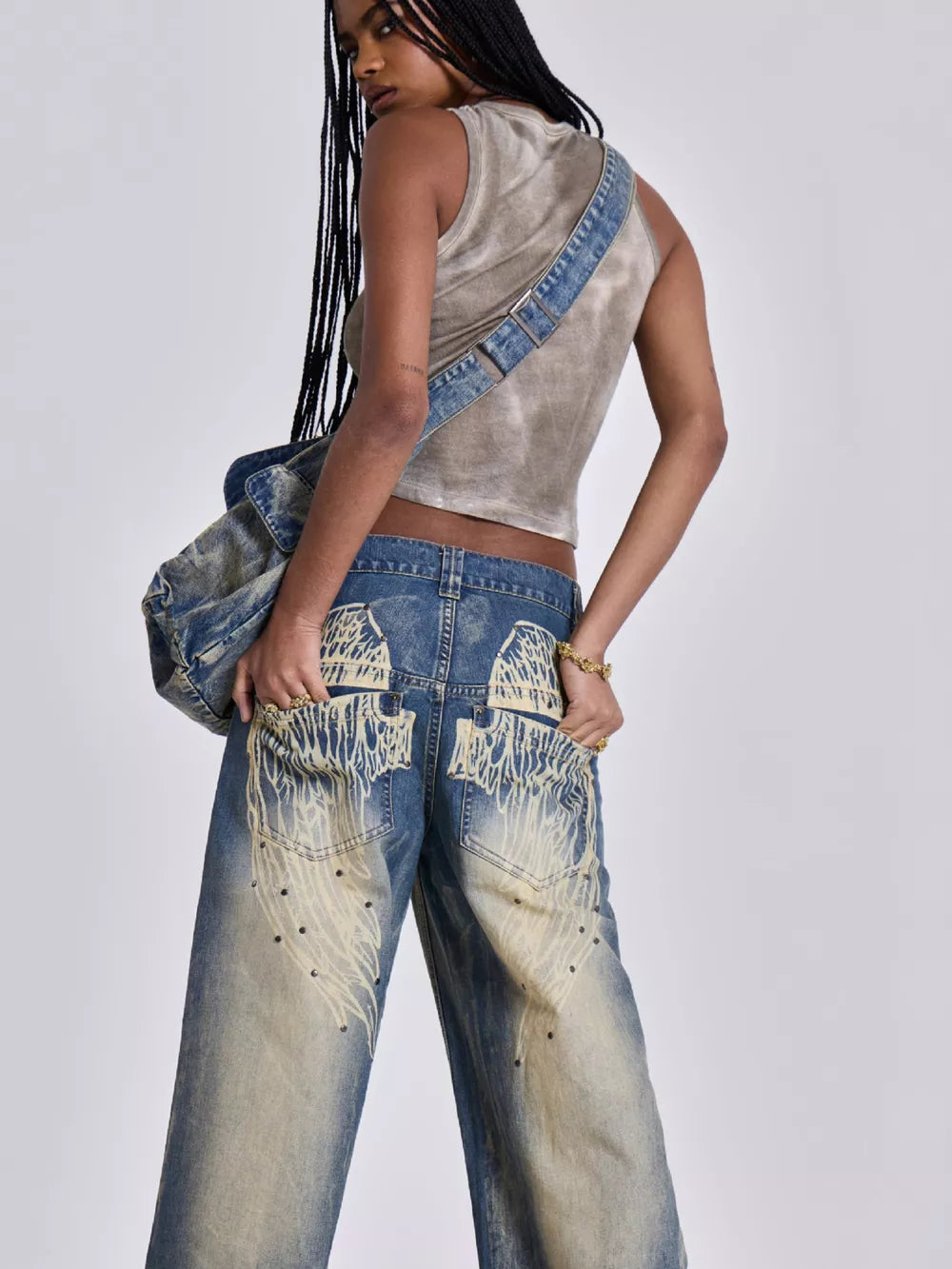 Blue wide leg jeans with vintage wash, studded details, and distressed graphic pockets.