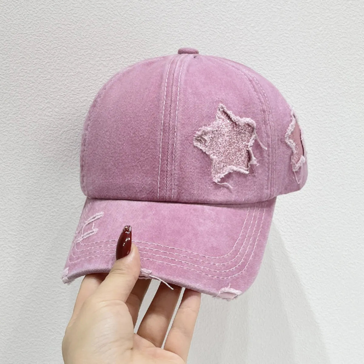 Stellar snapback cap in dusty pink with distressed star patches and frayed brim.