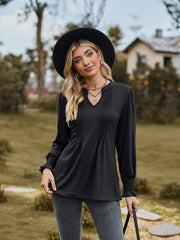 Black long sleeve blouse with V-neck, pleated yoke, and shirred cuffs.