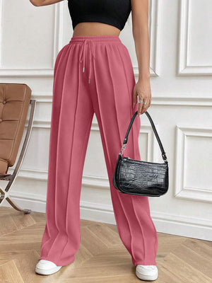 Dusty pink pleated palazzo drawstring trousers with a wide leg and a casual fit.