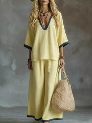 Yellow V-neck two-piece set with contrast trim and wide-leg pants.