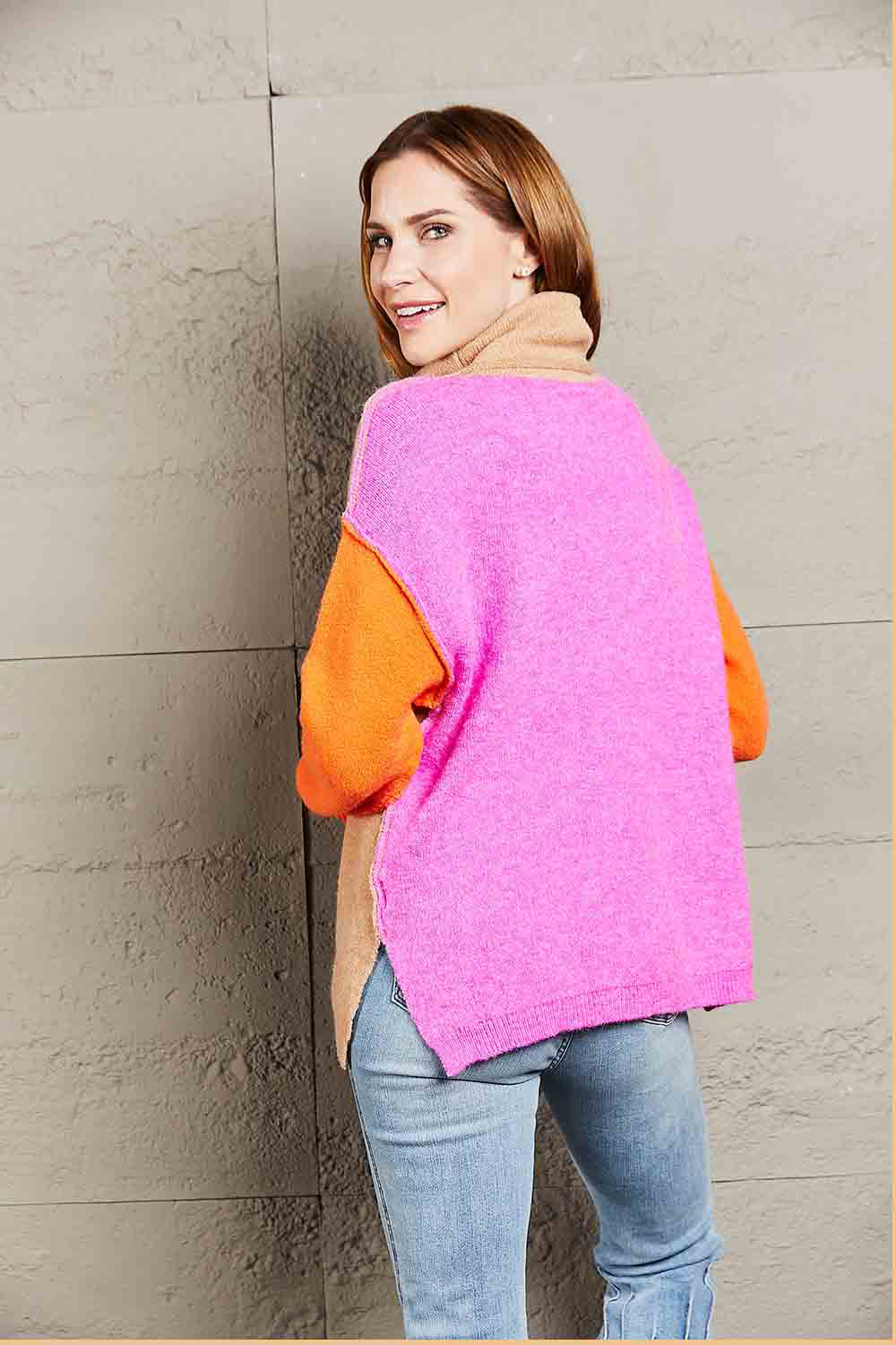 Colorblock turtleneck sweater with asymmetric hem in pink and orange with khaki accents.