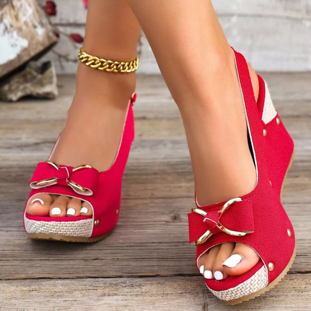 Red peep toe wedge sandals with decorative bow and adjustable strap.