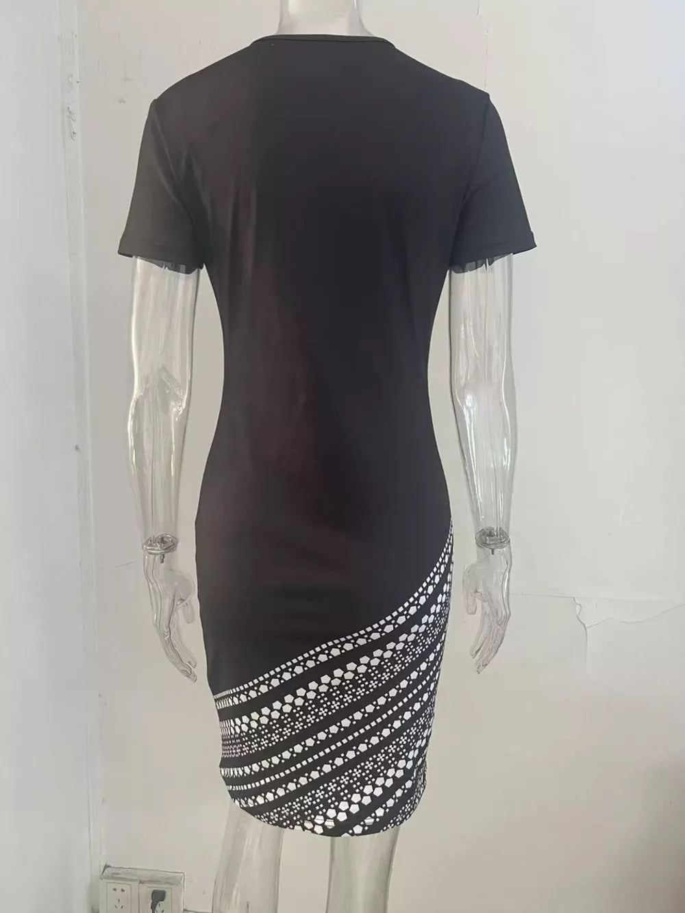 Black bodycon mini dress with geometric print detail on the hem.