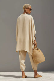 Beige linen two-piece set with relaxed fit tunic and cuffed pants, featuring a pocket detail.