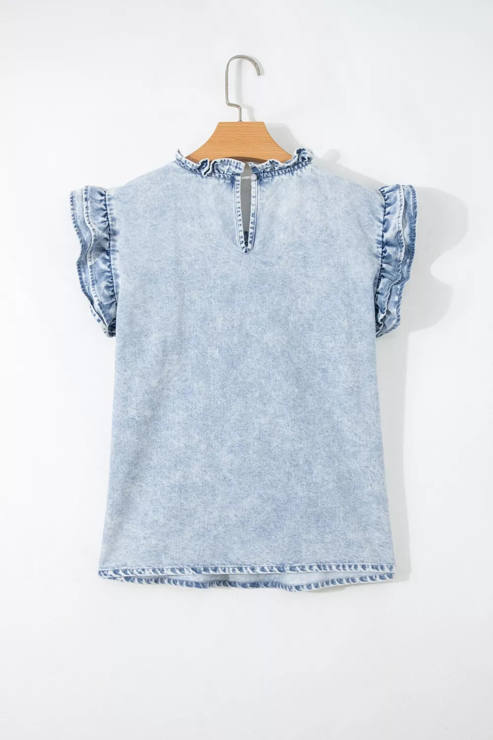 Light wash denim blouse with ruffled cap sleeves and mock neckline.