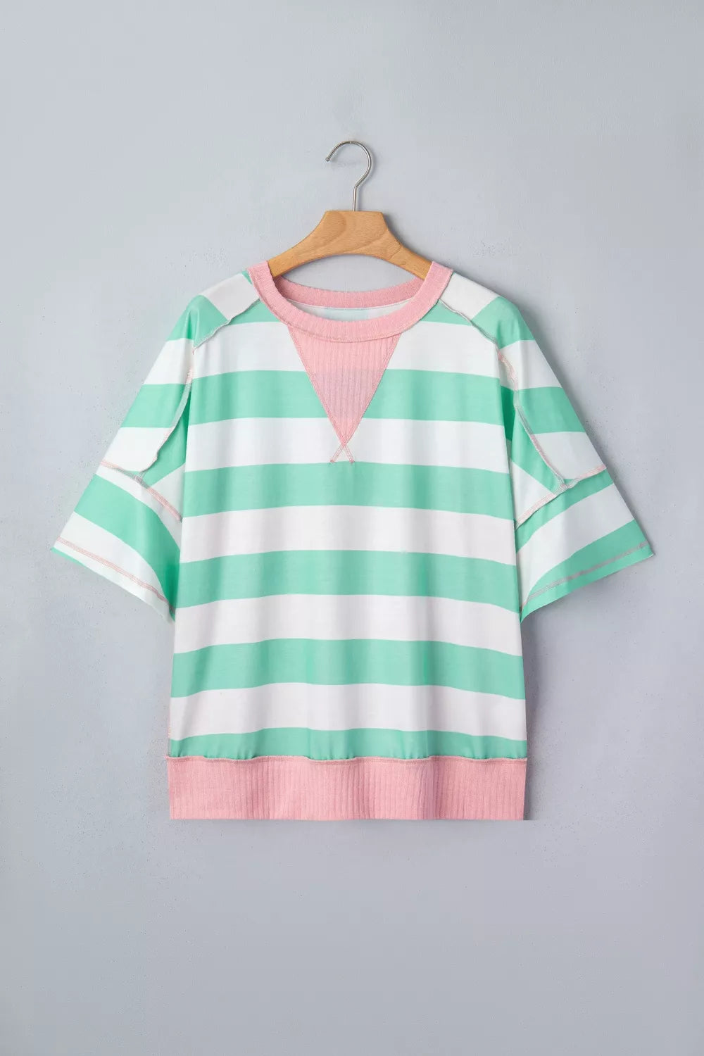 Oversized t-shirt with green and white stripes, pink neckline and hem, and exposed seams.