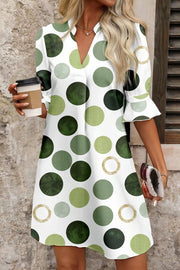 Playful polka dot mini dress with v-neck and flounce sleeves in green and gold tones.