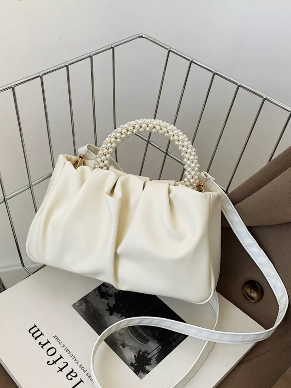 Elegant pearl-handled mini crossbody bag in rice white with ruched detailing.