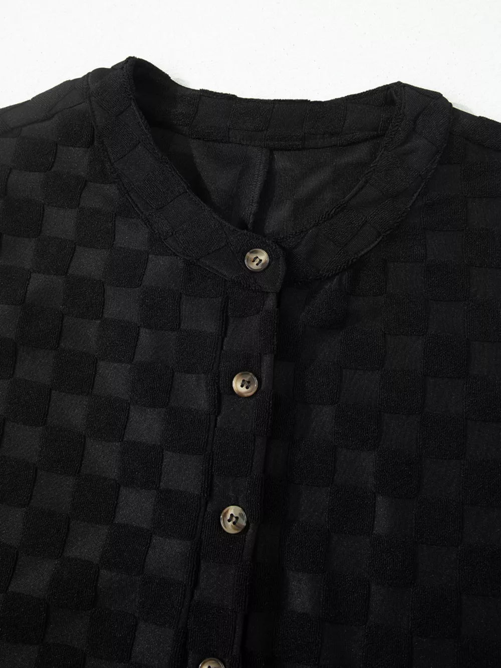 Black checkered wide-leg jumpsuit with button-front detail and round neckline.