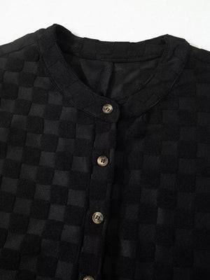 Black checkered wide-leg jumpsuit with button-front detail and round neckline.