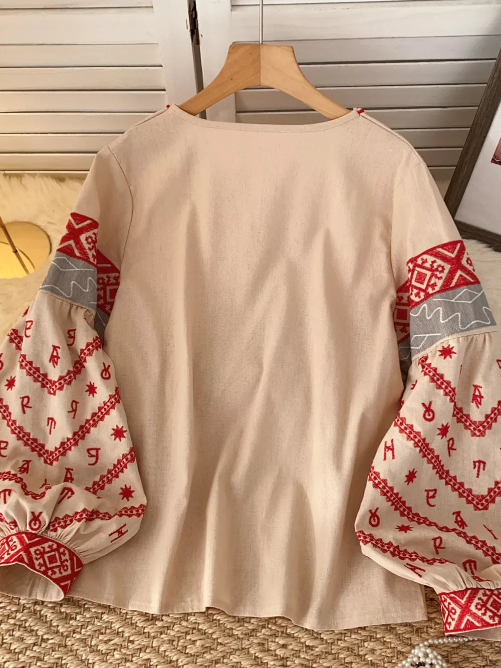Apricot folk-inspired shirt with red embroidered sleeves and tie neck detail.