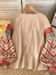 Apricot folk-inspired shirt with red embroidered sleeves and tie neck detail.