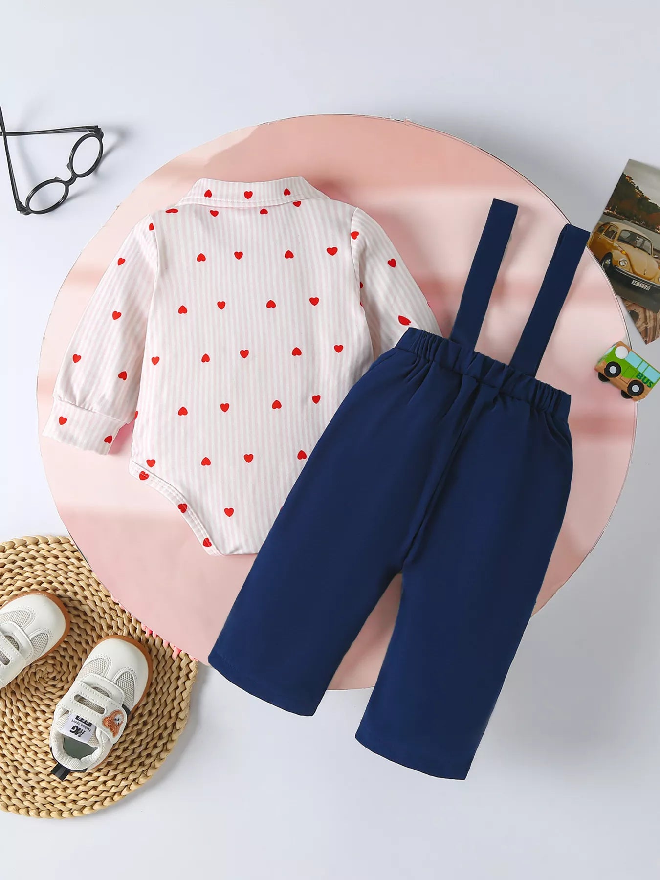 White striped bodysuit with red hearts, paired with navy suspender pants.