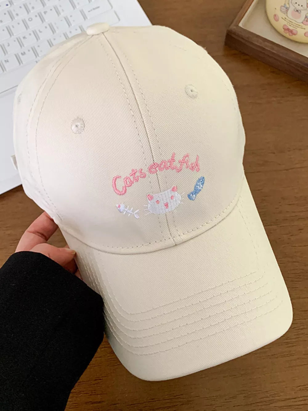 Off-white baseball cap with cat and fish embroidery and "Cats eat fish" text.