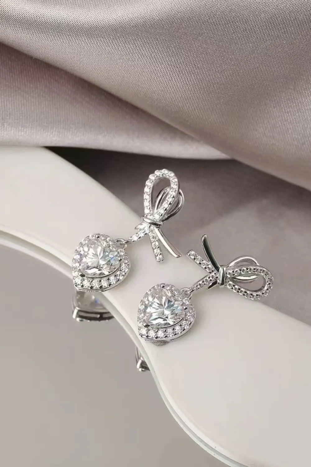 Silver moissanite heart drop earrings with bow detail, sterling silver