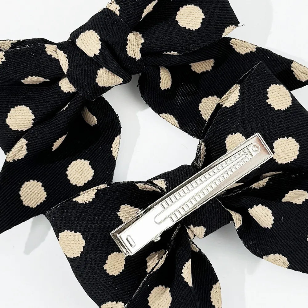 Black polka dot bow barrette with silver clip detail