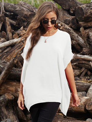 White asymmetrical sleeve blouse with draped hem, styled casually.