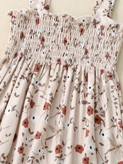 Baby jumpsuit with smocked bodice, floral print, and dragonfly accents.