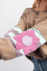 Camel raglan sleeve top with striped sleeves and a pink floral appliqué.